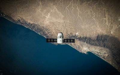 "Ein Weltraumsatellit schwebt über der Küste"; Foto: SpaceX auf Unsplash.