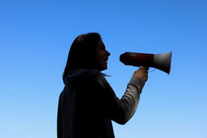 Frau mit Megafon; Bild: Juliana Romão auf Unsplash